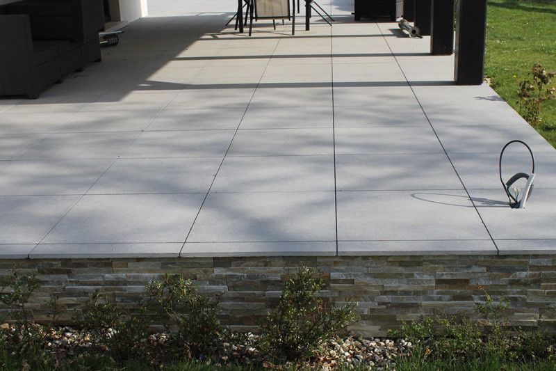 Pose d’une terrasse moderne en dalles grises avec finitions en pierre – Travaux de dallage et aménagement extérieur par AK Rénovation dans le Pays de Gex